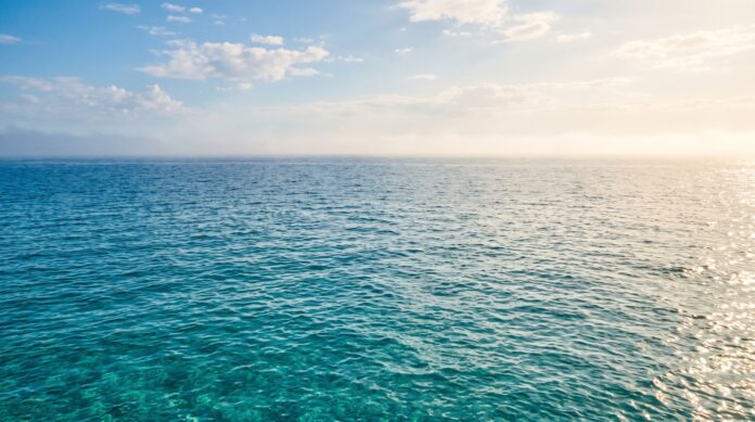 Superficie calma del Mar Mediterraneo illuminata dalla luce solare durante una giornata calda
