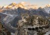 La Giornata del Leopardo delle Nevi: Custode Silenzioso del Terzo Polo e Baluardo della Biodiversità Globale Leopardo delle nevi accovacciato su una scogliera rocciosa delle montagne dell'Himalaya con vette innevate sullo sfondo